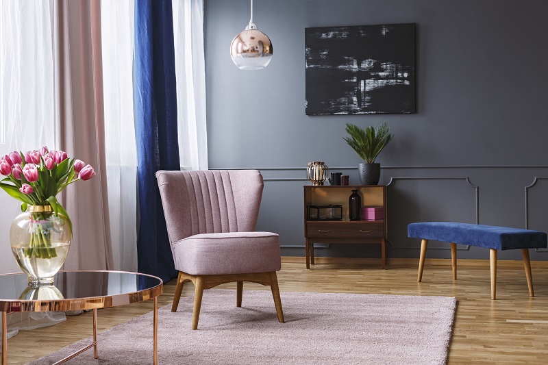 Real photo of a pink armchair standing on a rug and under a lamp